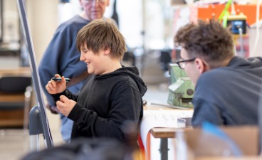 Schüler schreibt Bauplan des Prototyp Schüler schreibt Bauplan des Prototyp auf ein Flipchart