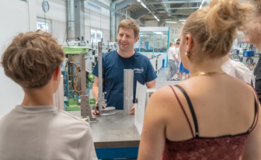 Mitarbeiter des Unternehmens erklärt Werkstück Mitarbeiter des Unternehmens erklärt einem Schüler und einer Schülerin in der Werkstatt, den Aufbau des Werkstücks