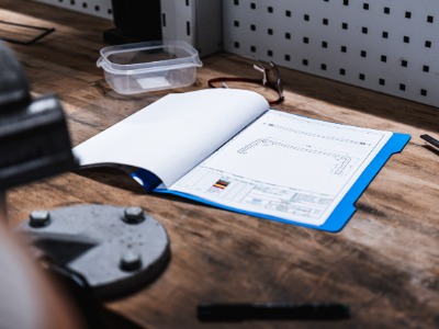 Schnellhefter mit technischer Zeichnung liegt auf einer WEkrbank 