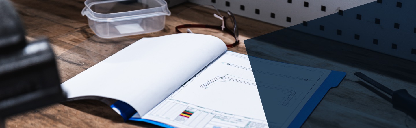 Eine Mappe mit einer technischen Zeichnung liegt auf einer Werkbank